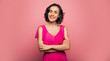 © My Ocean studio - True lady. Close-up photo of a charming healthy woman in a fuchsia dress, who is looking in the camera and smiling, while standing with her arms folded.