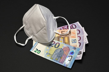 The cost of COVID-19 pandemic concept with ffp2 or KN95 prevention mask and euro currency on black background.