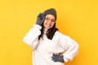 © luismolinero - Young woman with winter hat over isolated yellow background with glasses and smiling