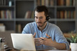 © fizkes - Confident man teacher coach wearing headset speaking, holding online lesson, focused student wearing glasses looking at laptop screen, studying, watching webinar training, listening to lecture