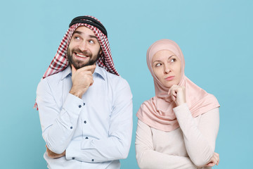 Poster - Pensive young couple friends arabian muslim man wonam in keffiyeh kafiya ring igal agal hijab clothes isolated on blue background studio. People religious lifestyle concept. Put hand prop up on chin.