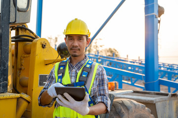 Aufkleber - Engineering wearing a yellow safety helmet standing In front of the backhoe And are using tablet to working with construction.