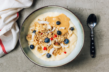 Wall Mural - Morning healthy breakfast bowl with yogurt, muesli, blueberry, banana, coconut on the concrete background.