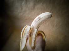 Yellow Overripe Banana On A Dark Background. Banana In Hand