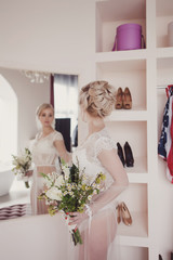 Wall Mural - Charming bride with bouquet in dressing gown posing in bedroom