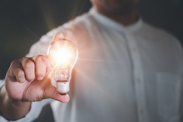 Poster - Businessman holding a bright light bulb. Concept of Ideas for presenting new ideas Great inspiration and innovation new beginning.