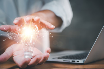 Poster - Businessman showing a bright light bulb in his hand, Success is achieved through creativity, innovation and inspiration. Concept of new idea and innovation.