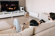 © Bostan Natalia - Back view of a couple of man and woman playing video game on a console, sitting on couch in living room.