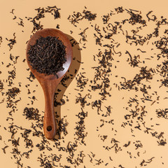 Wall Mural - Dry Puer tea leaves in a wooden spoon on a beige background,hard light