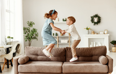 happy siblings jumping on sofa.