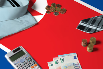 North Korea flag on minimal money concept table. Coins and financial objects on flag surface. National economy theme.