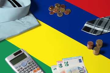 Mauritius flag on minimal money concept table. Coins and financial objects on flag surface. National economy theme.