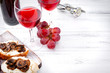 glasses of red wine, ,  bottle  , grapes, corkscrew,  snacks with mushrooms  and  cheese   on a white wooden background, copy space,