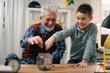 © JustLife - Grandpa and grandson saving money. Grandfather teaching grandchild how to save money.