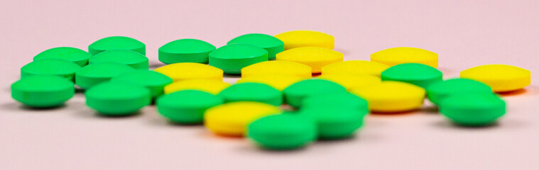 Wall Mural - Green and yellow medical pills on a pink background.