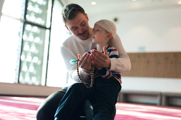 Wall Mural - Muslim father and son praying together. Muslim dad and son praying in the mosque.