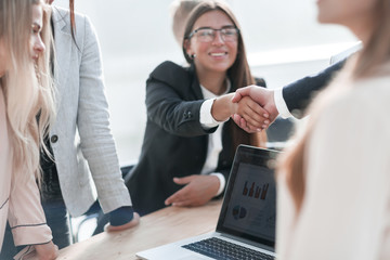 close up. smiling businesswoman shaking hands with her business partner