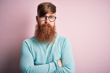 Poster - Handsome Irish redhead man with beard wearing glasses over pink isolated background skeptic and nervous, disapproving expression on face with crossed arms. Negative person.