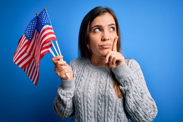 Sticker - Young patriotic woman holding usa flag on independence day 4th of july over blue background serious face thinking about question, very confused idea