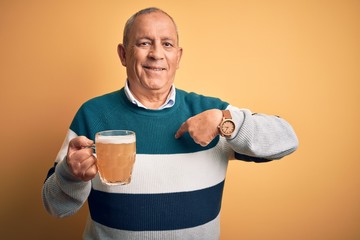 Sticker - Senior handsome man drinking jar of beer standing over isolated yellow background looking confident with smile on face, pointing oneself with fingers proud and happy.