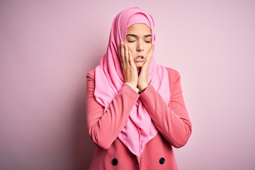 Poster - Young beautiful girl wearing muslim hijab standing over isolated pink background Tired hands covering face, depression and sadness, upset and irritated for problem