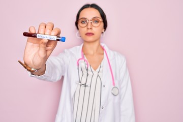 Wall Mural - Beautiful doctor woman with blue eyes wearing stethoscope holding coronavirus test tube with a confident expression on smart face thinking serious