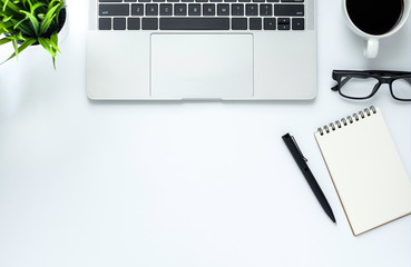 Workplace in office with white desk. Top view from above of laptop with notepad and coffee. Space for modern creative work of designer. Flat lay with blank copy space. Business and finance concept.