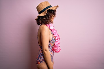 Sticker - Young beautiful arab woman on vacation wearing swimsuit and hawaiian lei flowers looking to side, relax profile pose with natural face with confident smile.