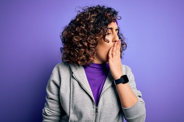 Sticker - Beautiful curly arab sportswoman doing sport wearing sportswear over purple background bored yawning tired covering mouth with hand. Restless and sleepiness.