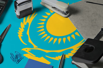 Kazakhstan flag with office clerk workplace background. National stationary concept with office tools.