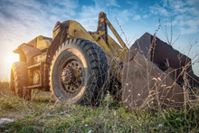 Old Yellow Wheel Loader Left In The Field. Large Rusty Digger Excavator, HDR Image, Blue Sky In The Background.