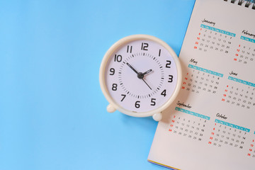 Wall Mural - analog white clock with calendar on blue paper background, flat lay, deadline concept