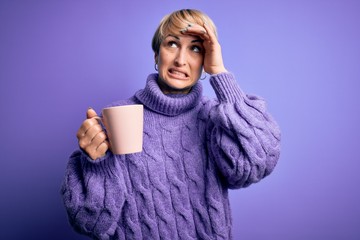 Poster - Young blonde woman with short hair wearing winter sweater drinking a cup of hot coffee stressed with hand on head, shocked with shame and surprise face, angry and frustrated. Fear and upset