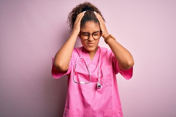 Poster - African american nurse girl wearing medical uniform and stethoscope over pink background suffering from headache desperate and stressed because pain and migraine. Hands on head.