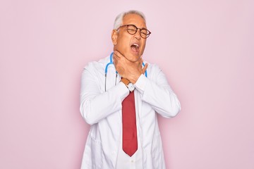 Sticker - Middle age senior grey-haired doctor man wearing stethoscope and professional medical coat shouting suffocate because painful strangle. Health problem. Asphyxiate and suicide concept.