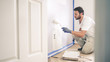 © RightFramePhotoVideo - Painter man painting the wall in home, with paint roller and white color paint.