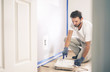 © RightFramePhotoVideo - Painter man painting the wall in home, with paint roller and white color paint.