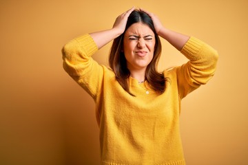 Poster - Young beautiful woman wearing casual sweater over yellow isolated background suffering from headache desperate and stressed because pain and migraine. Hands on head.