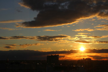 Wall Mural - red sun at sunset or dawn at dusk low above the horizon shrouded in smoke from the chimneys of the p