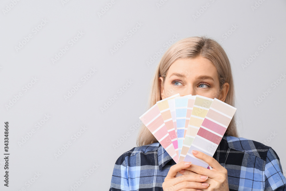 Young woman with color swatches on grey background