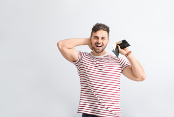 Wall Mural - Happy man with purse on light background