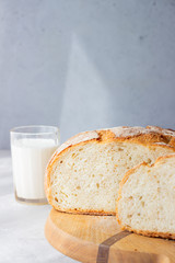 Poster - Sliced loaf of freshly baked artisan sourdough bread and a glass of milk. No knead bread. Light grey concrete background.