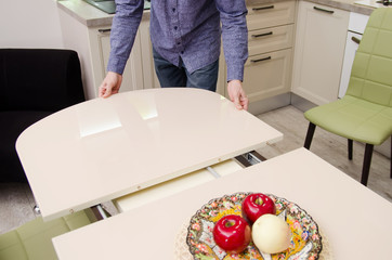 Wall Mural - man spreads a sliding glossy dining table on which stands a plate with artificial fruit