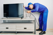 Serious Young Vietnamese Repairman Installing Tv Set In Apartment Of Customer