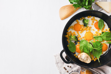 Wall Mural - Healthy breakfast table with fry pan eggs with spinach on white background with copy space top view