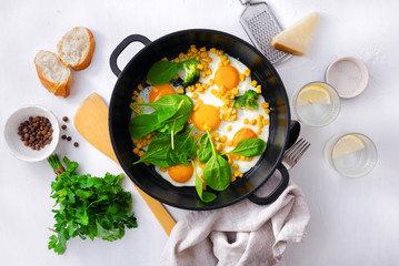 Poster - Healthy breakfast table with fry pan eggs with spinach on white background top view