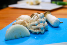 Slice Of Onion, White Beech Mushroom, King Trumpet Mushroom On A Blue Cutting Board. Various Type Of Mushrooms And Cooking Ingredients.