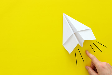 Wall Mural - concept image of person hand directing paper plane over yellow background