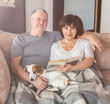 © Tatyana Gladskih - Happy elderly couple sitting on sofa at home