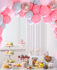 Baby shower party for girl. Tasty treats on table in room decorated with balloons